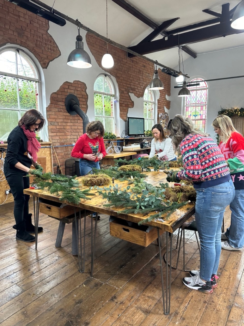 Participants crafting a handmade Christmas wreath with natural materials at an Xmas wreath making workshop in Cheshire