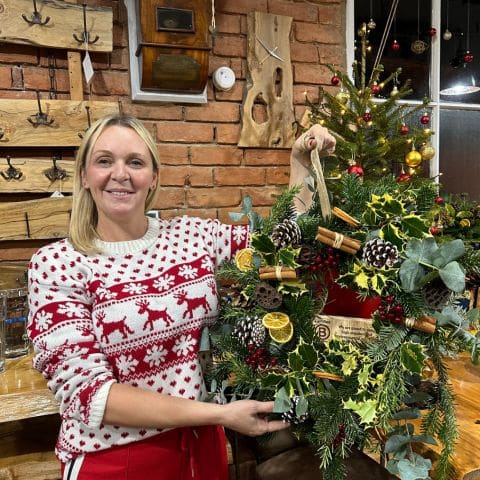 Cheryl White smiling at a Christmas Wreath Workshop, sharing how the relaxed atmosphere and guidance made her first experience enjoyable.