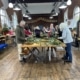 Mixed group of men and women smiling while working on handmade wreaths at a corporate Christmas workshop.