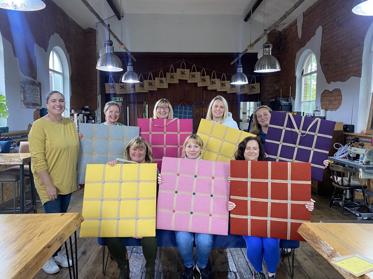 Group of participants proudly showing their handmade creations at the end of a wellbeing workshop.