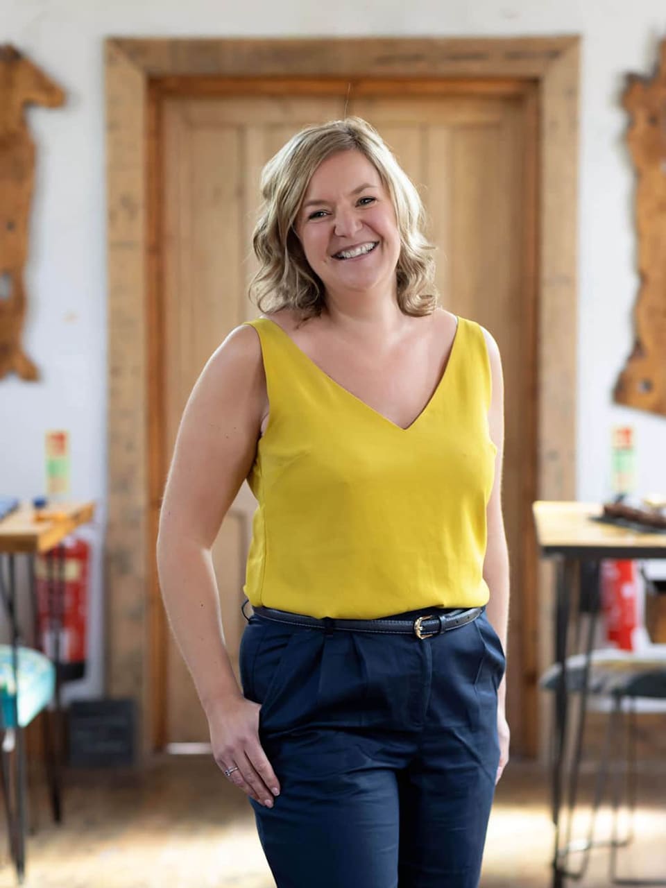Emma Semper Hopkins smiling at a wooden table inside the chapel studio in Cheshire.