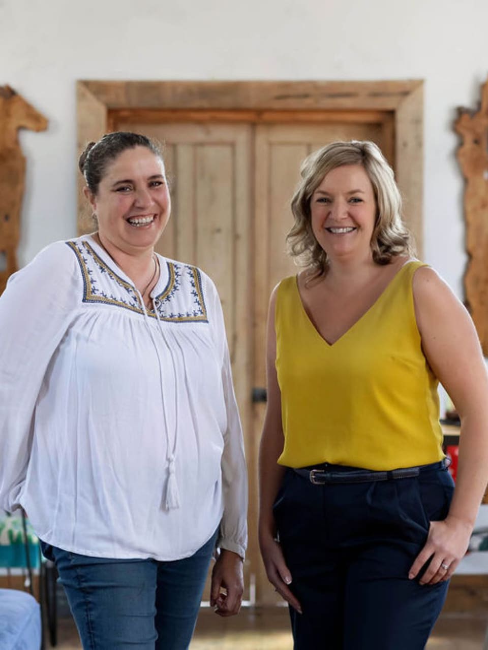 emma-and-ros-semphopkins-team-photo_ Ros and Emma standing together smiling inside the chapel workshop.