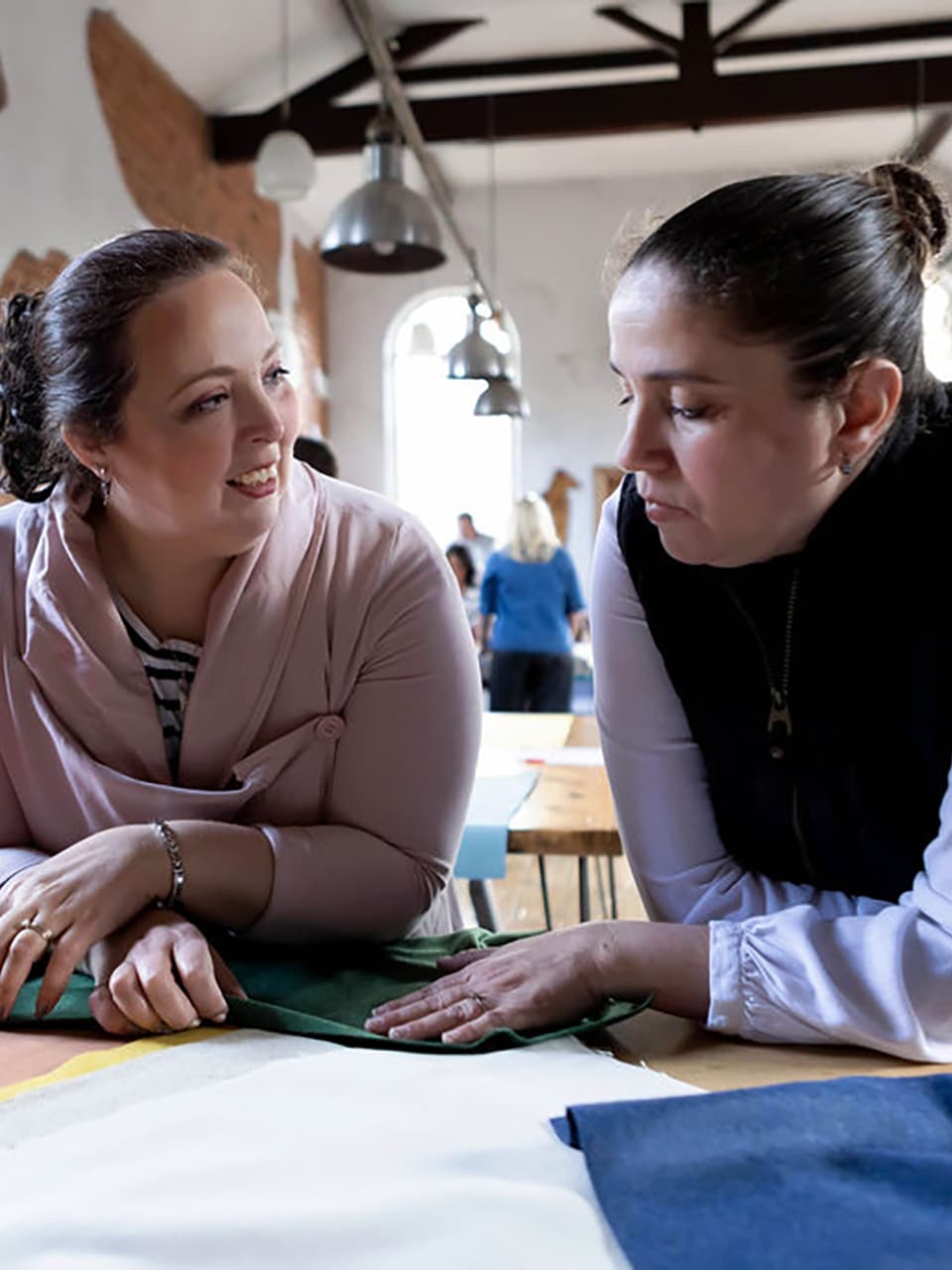 ros-teaching-fabric-selection Ros guiding a workshop guest through fabric choices during a creative upholstery session.