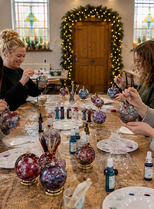 Guests creating marbled glass baubles during a luxury Christmas workshop in Cheshire chapel studio